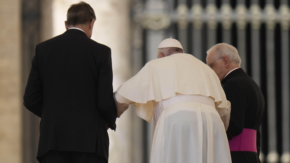 Le pape François s'appuie sur un collaborateur pour marcher.