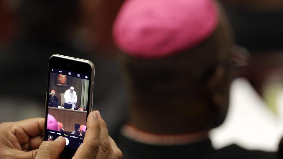 Quelqu'un prend une photo du pape avec son téléphone lors de l'ouverture du synode au Vatican.