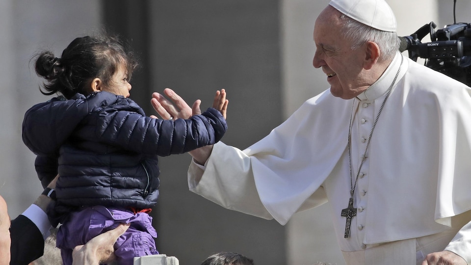 Le pape sourit à une fillette qui lui est présentée.