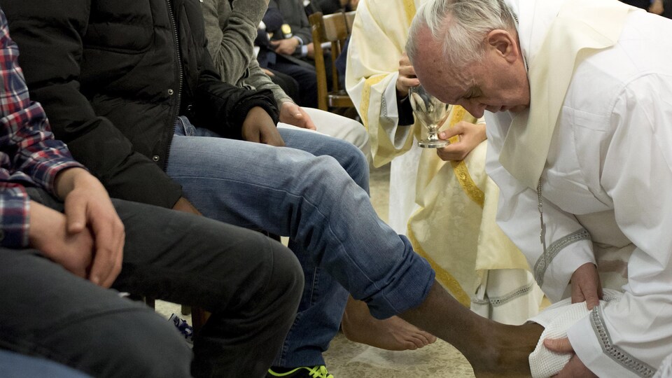 Le pape François, à genoux, lave les pieds de prisonniers.