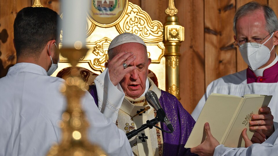 Le pape Francois, avec des aides, récite la messe au micro.