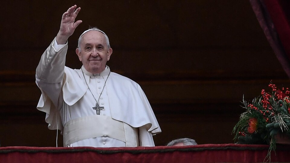 Le pape François salue la foule de la main depuis le balcon du Vatican.