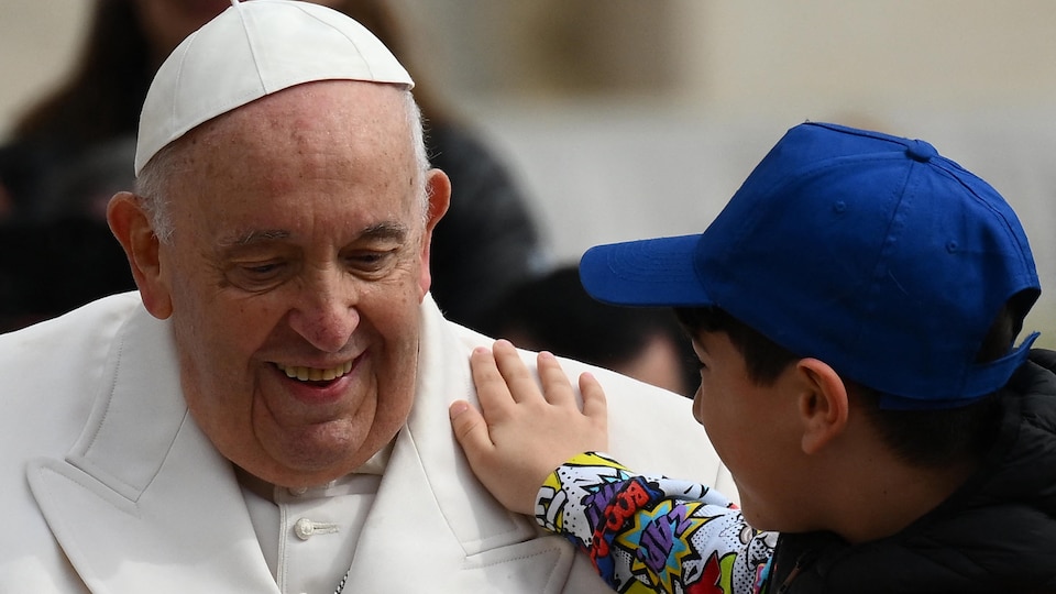 Un enfant place une main sur l'épaule du pape.