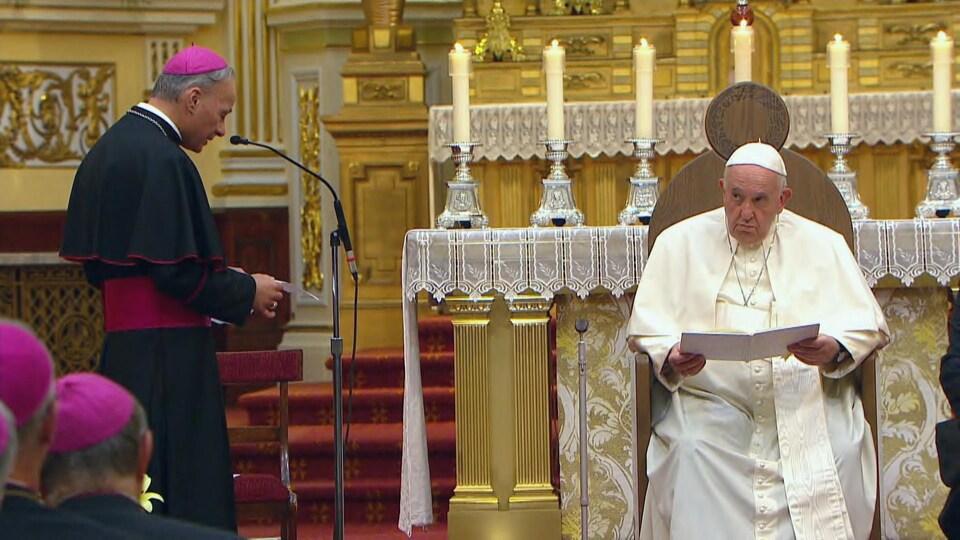 Assis sur son siège, devant l'autel, le pape François écoute les mots de bienvenue de Mgr Raymond Poisson.
