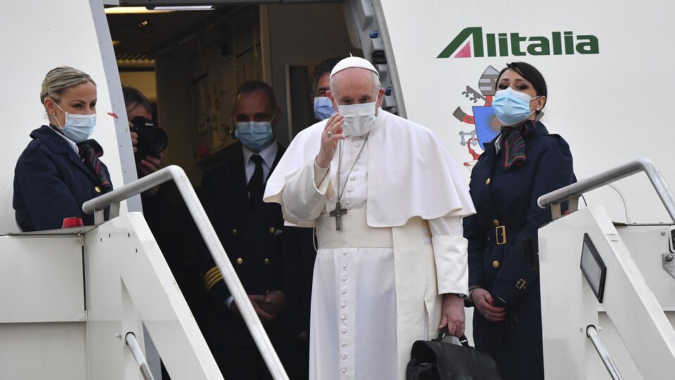 Le pape salue avant de monter à bord d'un avion.