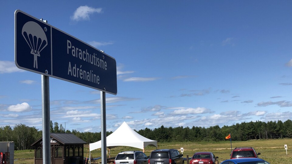 Pancarte de l'endroit avec des voitures dans le stationnement.