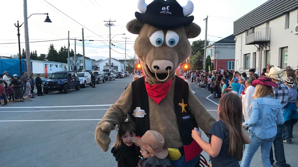 Trois enfants font une accolade à une mascotte de taureau.