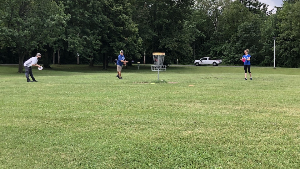 Trois personnes jouent au disque golf