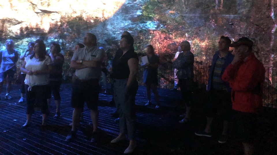 Des spectateurs assistent à un spectacle projeté sur le granit.
