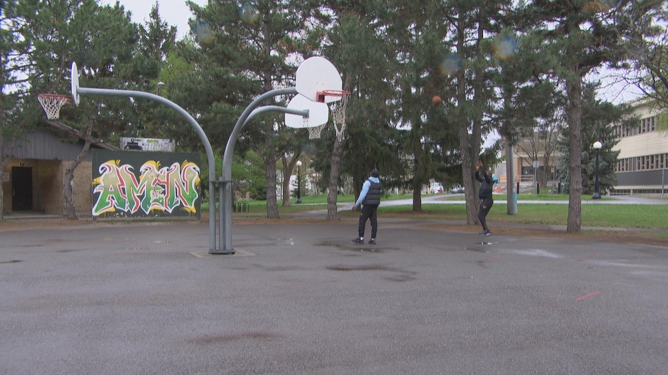 Ibrahima Doumbouya et Ezechiel Nana pratiquent leur lancer sur un terrain de basket extérieur.