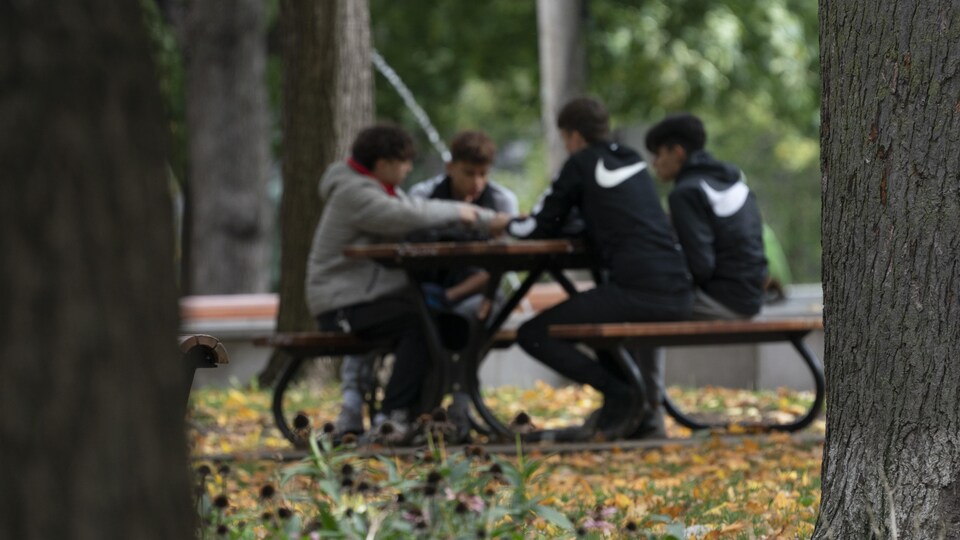 Quatre adolescents sont assis à une table dans un parc.