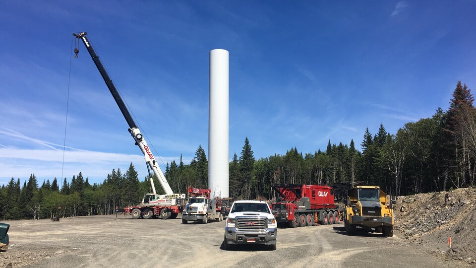 De l'équipement de construction devant le mât d'une éolienne sans hélice sur le site du futur parc éolien Nicolas-Riou.