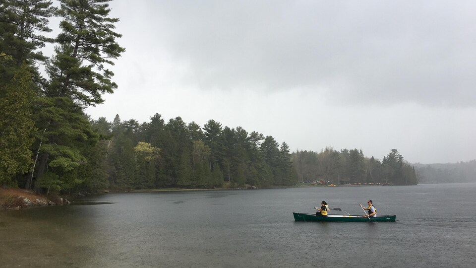 Des gens en canot sur un lac, pendant qu'il pleut.