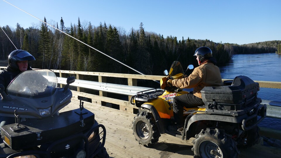 Deux quads passent sur un pont enjambant une rivière.