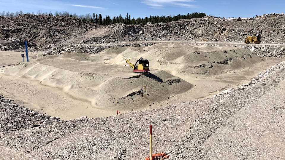 Une machine égalise une fondation en gravel.