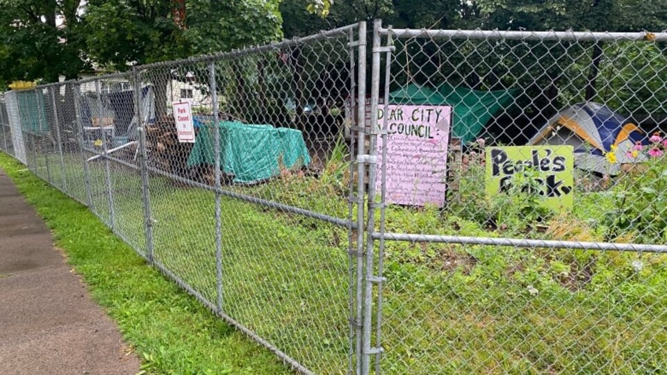 Une clôture a grillage autour du parc où il reste quelques tentes et affiches.