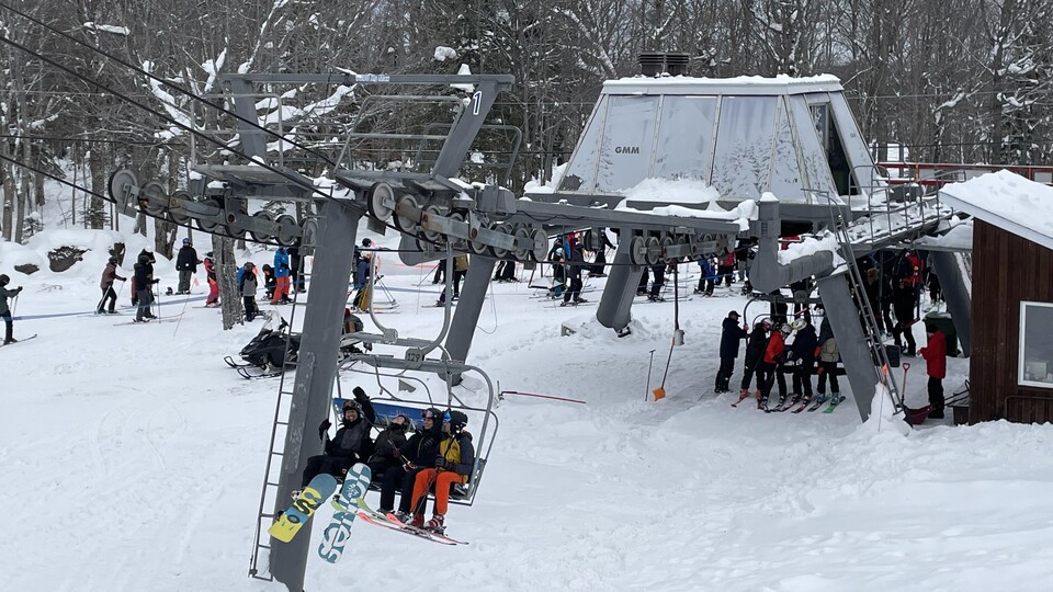Des gens envoient la main en embarquant dans le remonte-pente du parc du Mont-Comi.