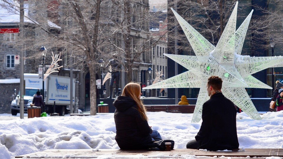 Un homme et une femme sont assis sur le banc d'un parc enneigé.
