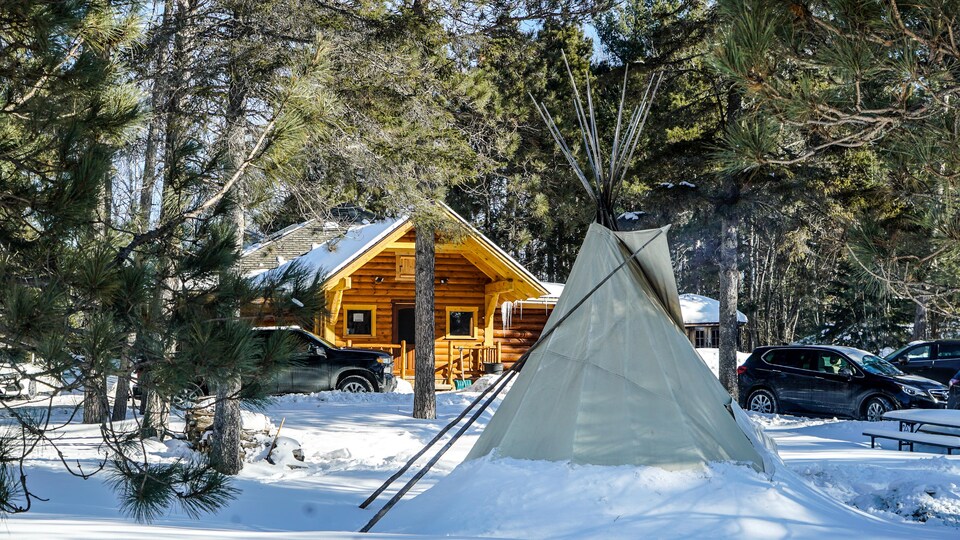 Un tipi devant un bâtiment en bois.