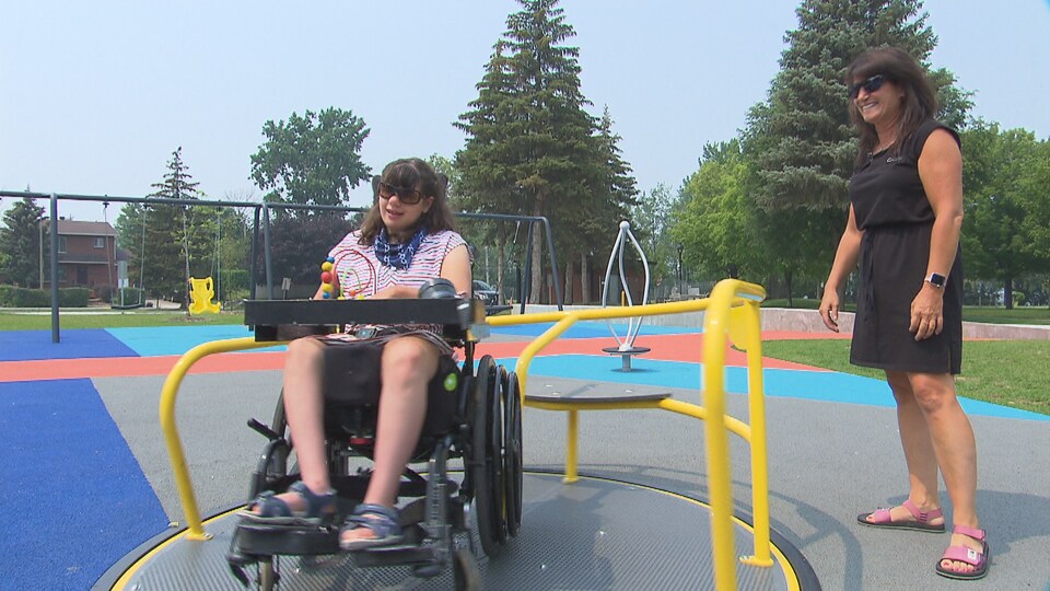 Une fille dans un fauteuil roulant et une femme dans un parc.