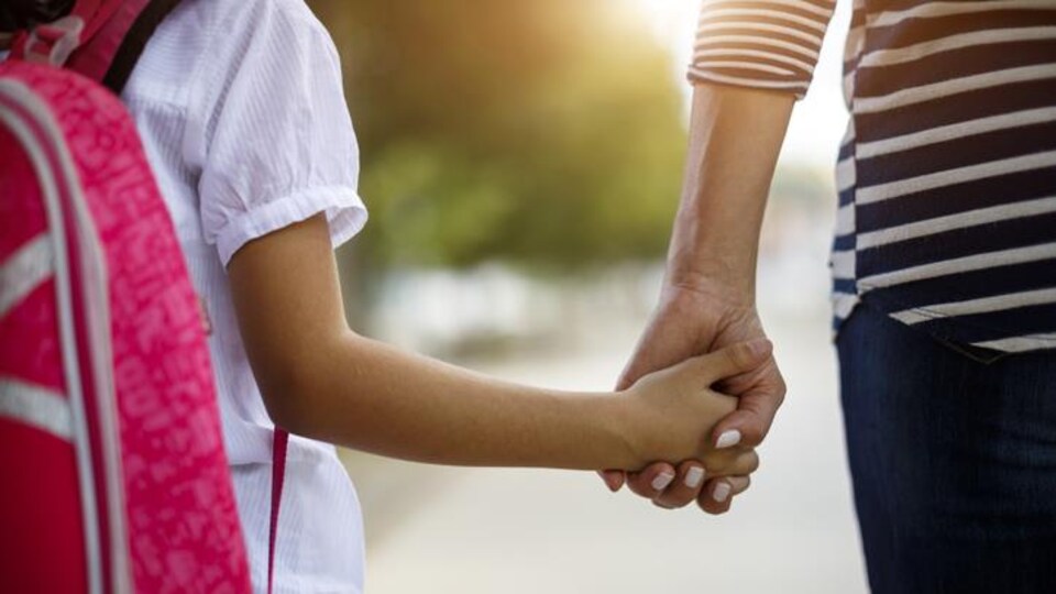 Une mère tient la main de sa fille.
