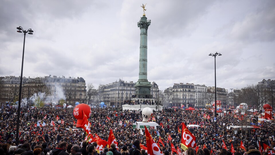 Des milliers de personnes sont attroupées sur la place de la Bastille arborant des drapeaux et des ballons à l'effigie de leurs associations syndicales. 
