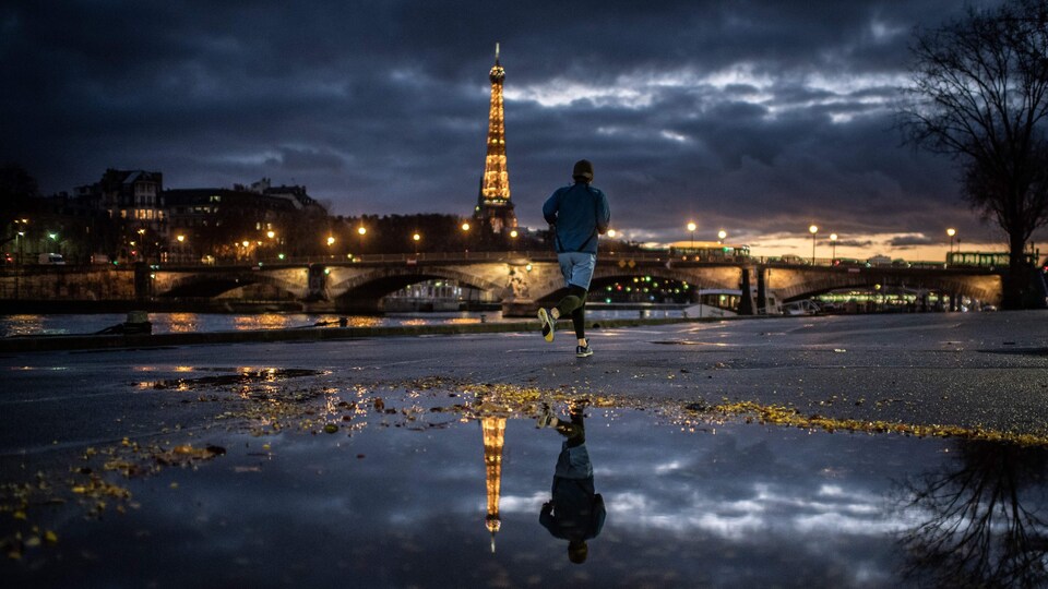Un coureur sur les bords de Seine avec la tour Eiffel illuminée en arrière-plan.