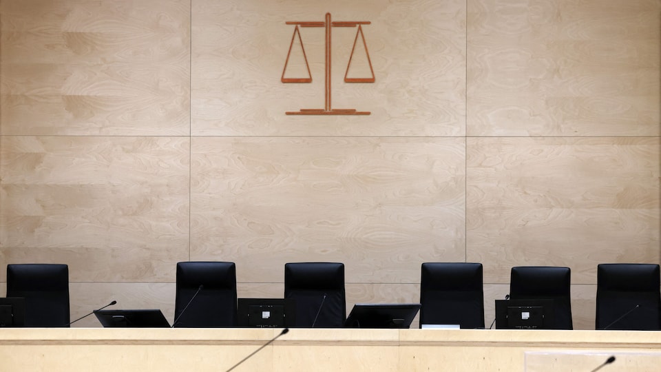 Une salle d'audience déserte avec, au mur, le symbole de la justice.