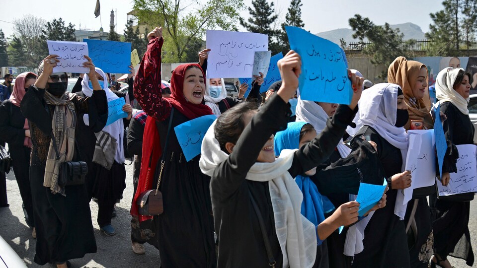 Plusieurs femmes voilées portant des affiches contre la décision des talibans de les bannir des écoles et des universités.