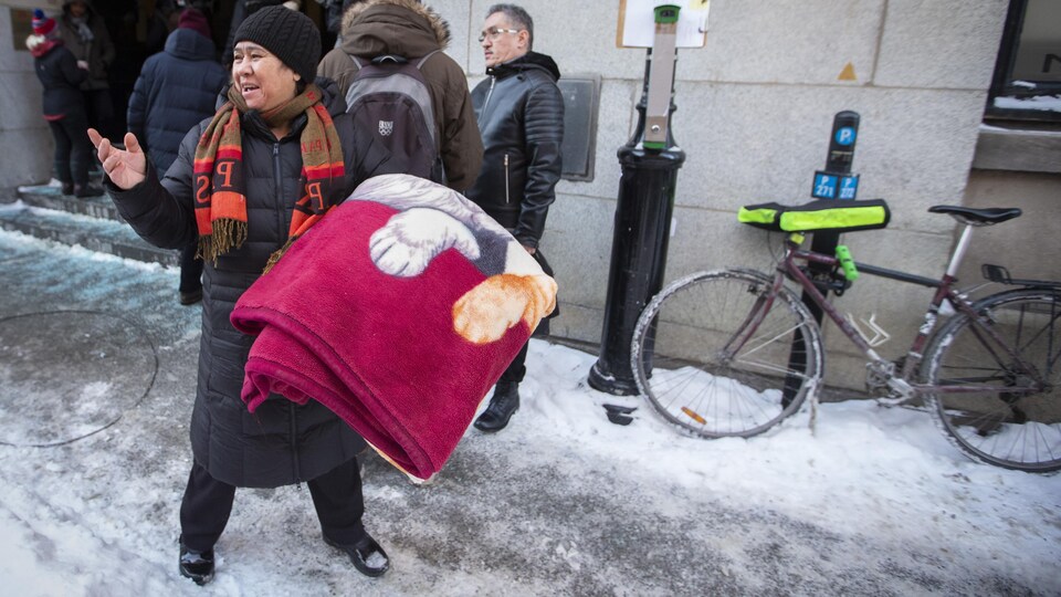 Une femme arrive devant le bureau d'Immigration Québec équipée d'une couverture.