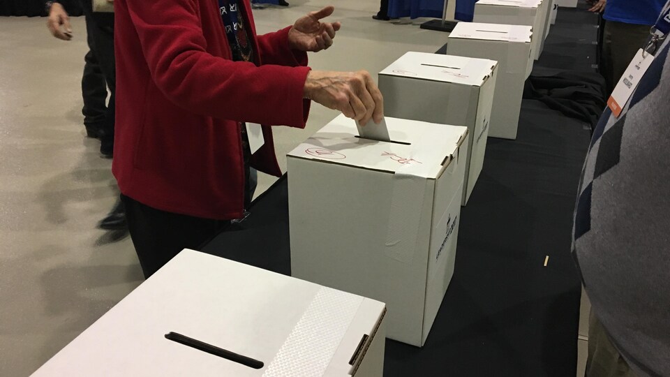 Une dame glisse une enveloppe dans une urne pour voter pour le nouveau chef du Parti progressiste-conservateur de l'Alberta.