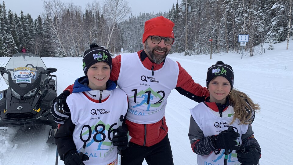 La famille sourit devant la piste de ski de fond.