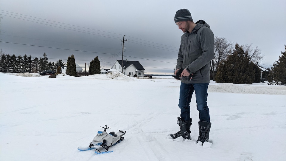Pascal Robert se sert d'une télécommande pour guider sa motoneige dans la neige.