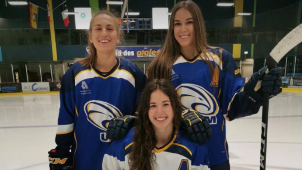 Three hockey players in the Aigles Bleues uniforms of the Université de Moncton.