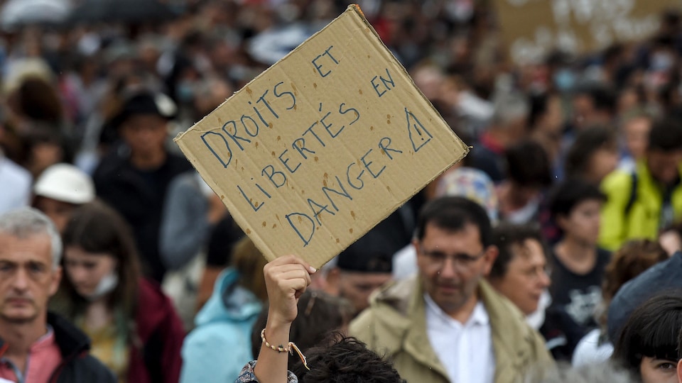 Une manifestante brandissant une pancarte indiquant «droits et libertés en danger».