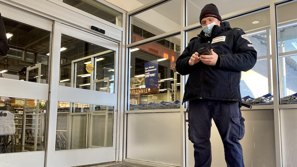 Un agent de sécurité tient un appareil pour lire les codes QR.