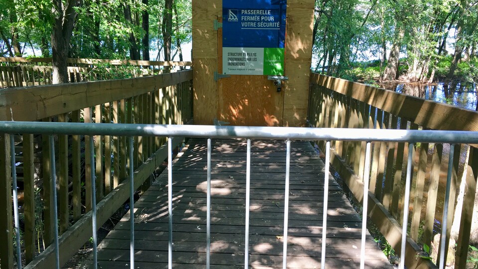 Une passerelle en bois qui est inaccessible aux passant puisqu'une affiche indique qu'elle est fermée au public. 