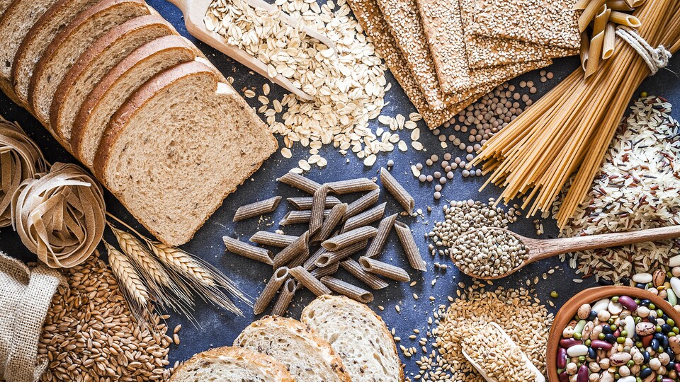 Du pain, des céréales, des pâtes et des légumineuses de toutes sortes sur une table.