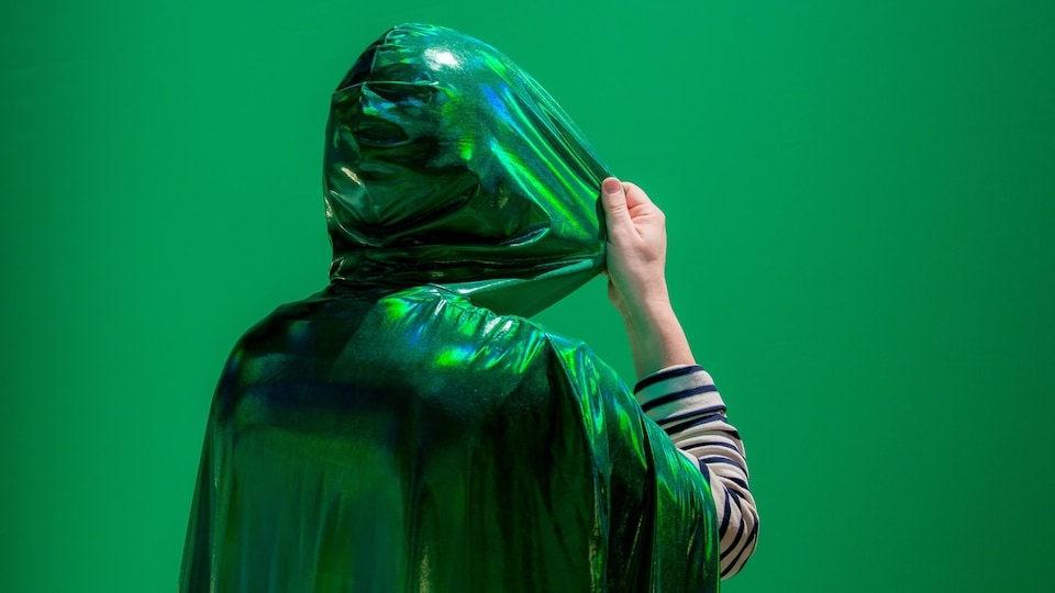 une personne de dos avec une capuche verte sur la tête.