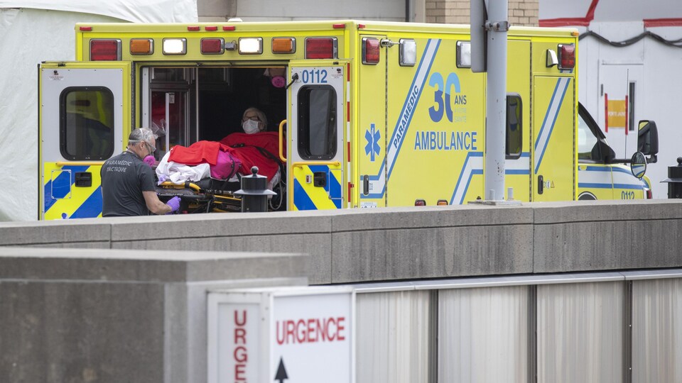 Une patiente placée sur une civière est extraite d'une ambulance près d'un hôpital. 