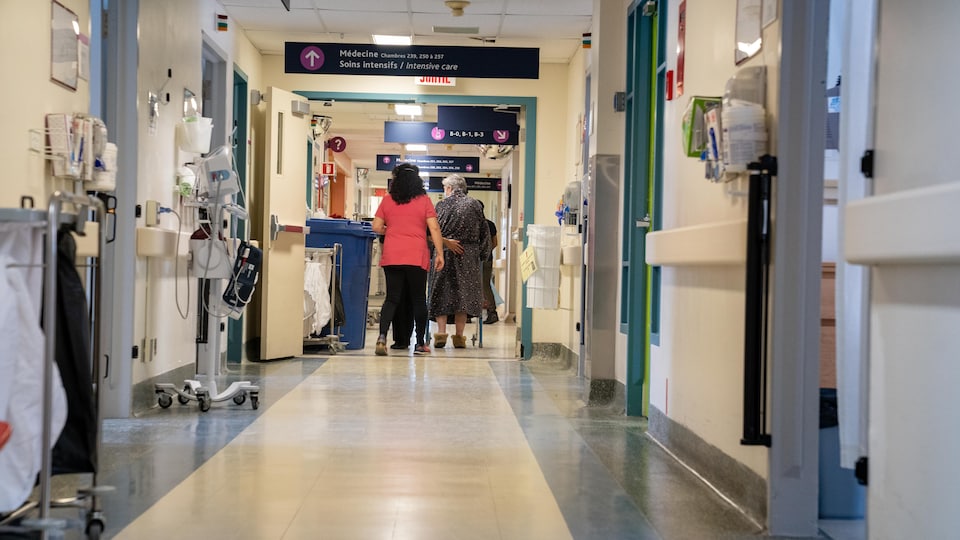 Une infirmière accompagne une patiente dans un couloir.