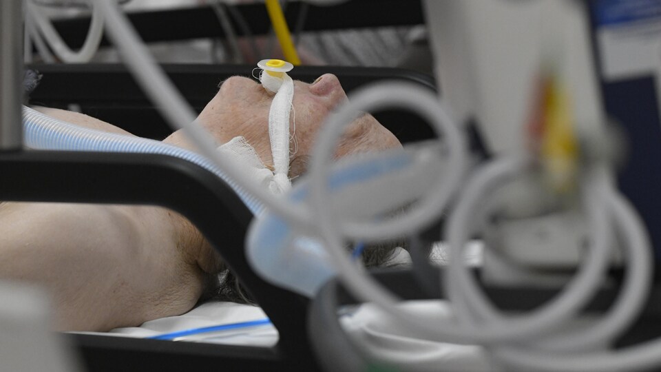 Une personne couchée sur le dos à l'hôpital avec un tube dans la bouche.