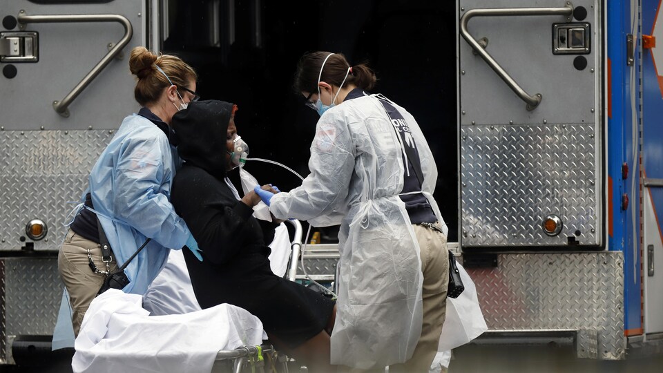 Des techniciens médicaux prennent en charge une patiente près d'une ambulance.