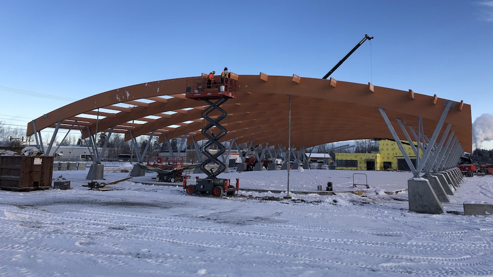 Des travailleurs construisent le toit de la patinoire.