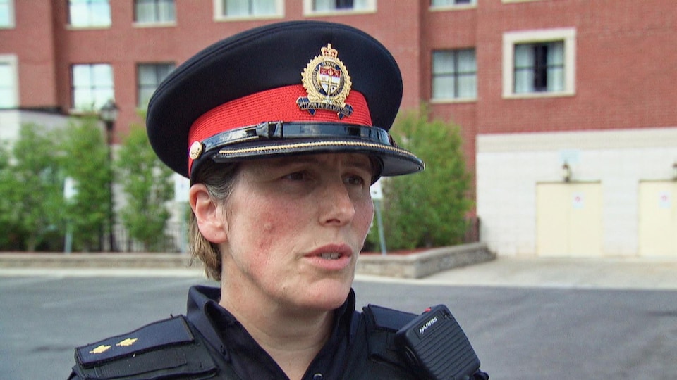 Une policière coiffée d'un chapeau en entrevue.
