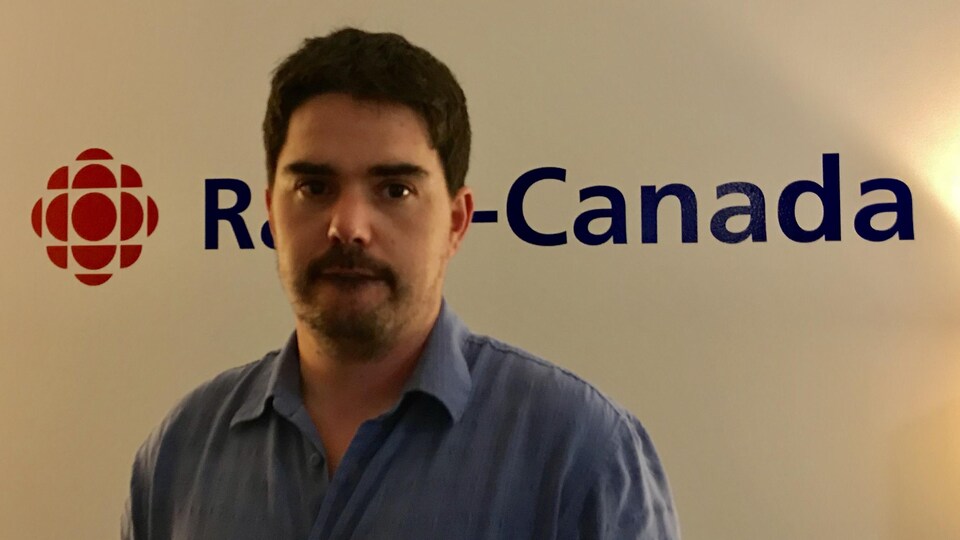 Patrick Binne devant le logo de Radio-Canada