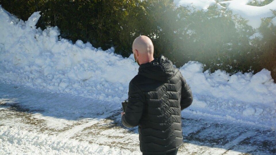 Un homme de dos marche à l'extérieur dans la neige.