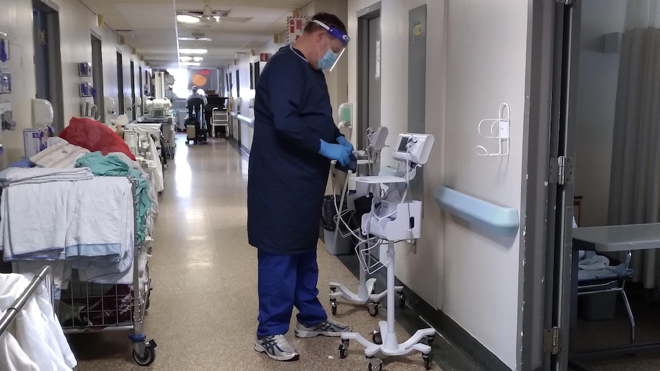 Un infirmier vêtu d'équipement de protection individuelle dans un couloir d'hôpital.