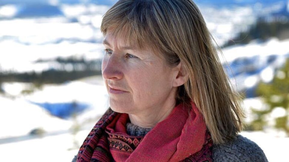 Patti Flather est à l'extérieur l'hiver et esquisse un sourire en regardant au loin.
