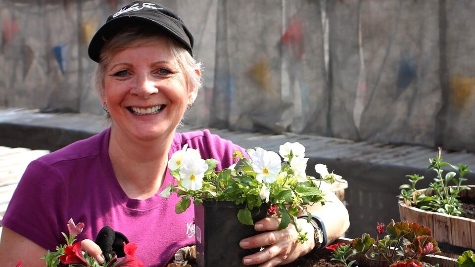Patty Minall près d'un pot de fleurs.
